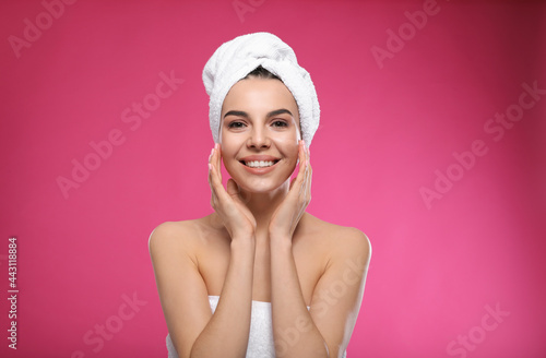Happy young woman with towel on head against pink background. Washing hair