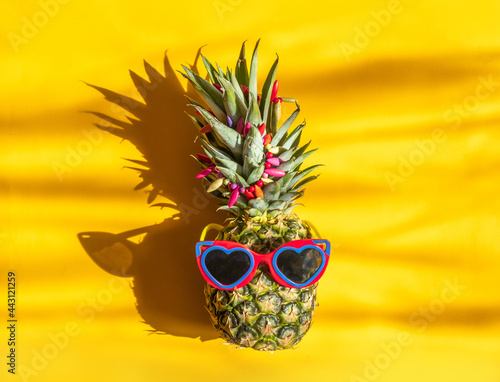 Pineapple hipster in sunglasses. Minimal concept, summer tropical pineapple.Hard shadows imitating sand