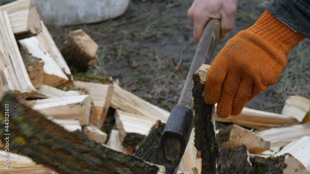 Man's hands chop large logs and tree trunks with ax for a future fire Man's hands chop large logs and tree trunks with ax for a future fire