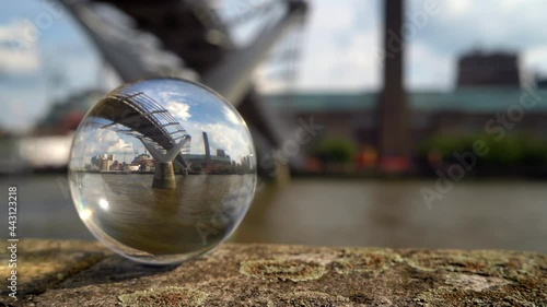 Tate Modern art gallery and the Millennium Bridge refracted in a glass sphere. Focus is on the refracted image. Shot from across the river. photo