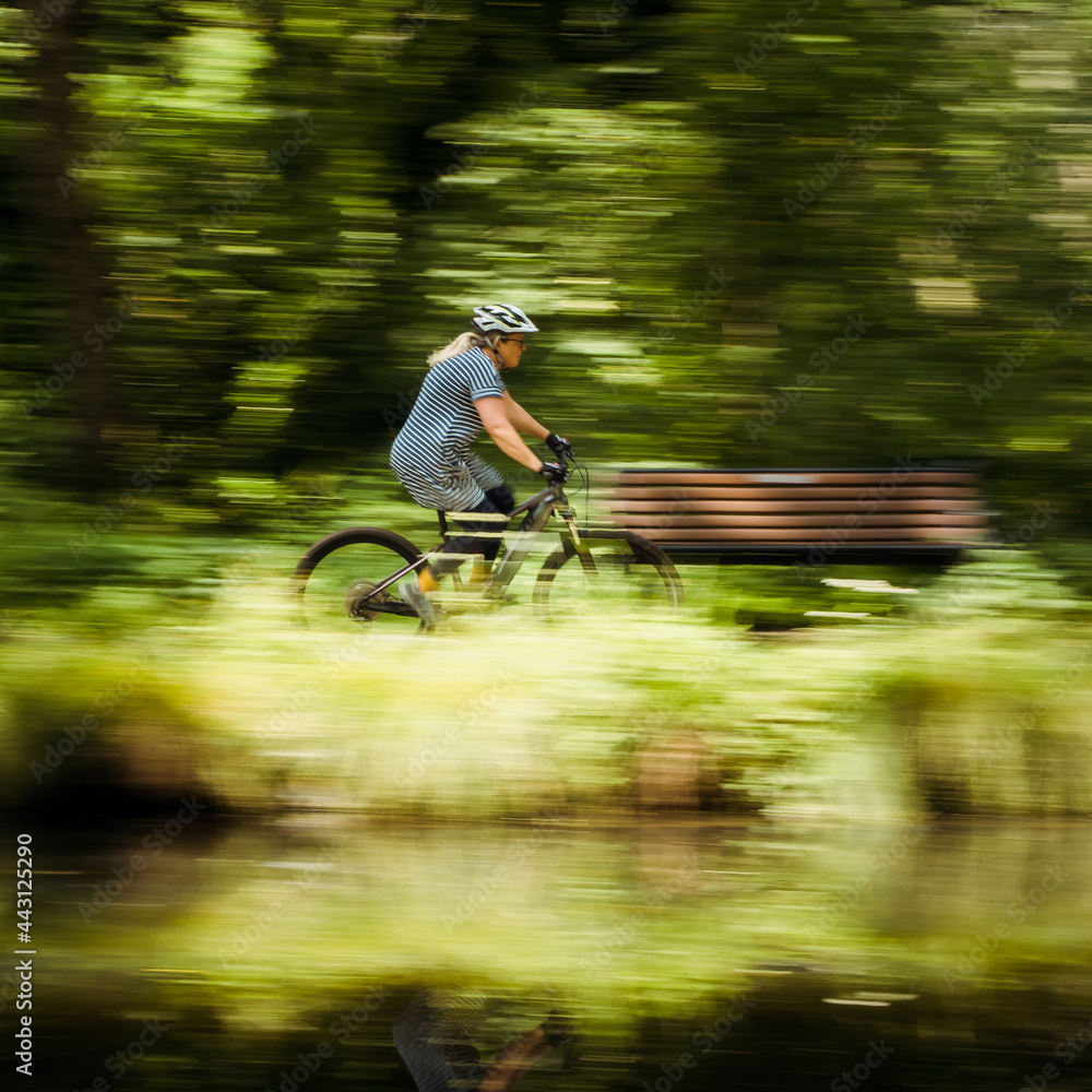 Fototapeta Woman cycling at speed by a canal