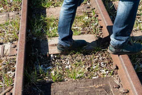 Feet stands on narrow gauge railway on spring day
