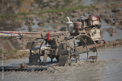 Close-up of muddy machine ploughing rice by traditional methods in ricefields of Laos photo
