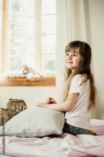 happy little girl in pajamas sitting on the bed