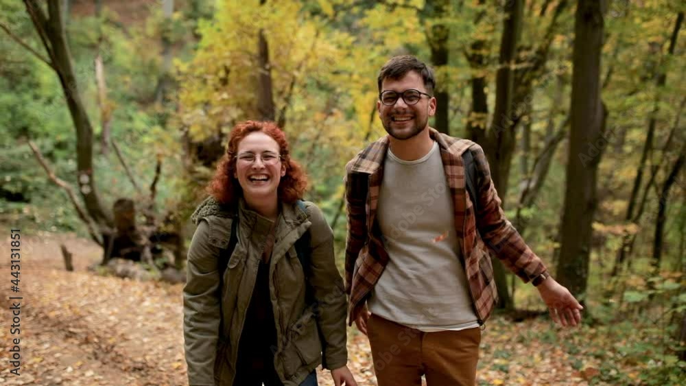 Two young hikers with backpack throwing leaves towards camera in forest. Two young hikers with backpack throwing leaves towards camera in forest.