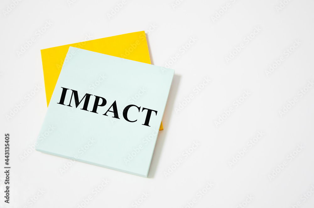 impact text written on a white notepad with colored pencils and a yellow background. word