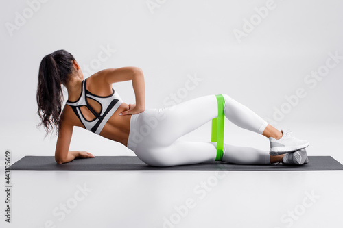 Fotografie, Tablou Fitness woman doing clamshell exercise for glutes with resistance band on gray background