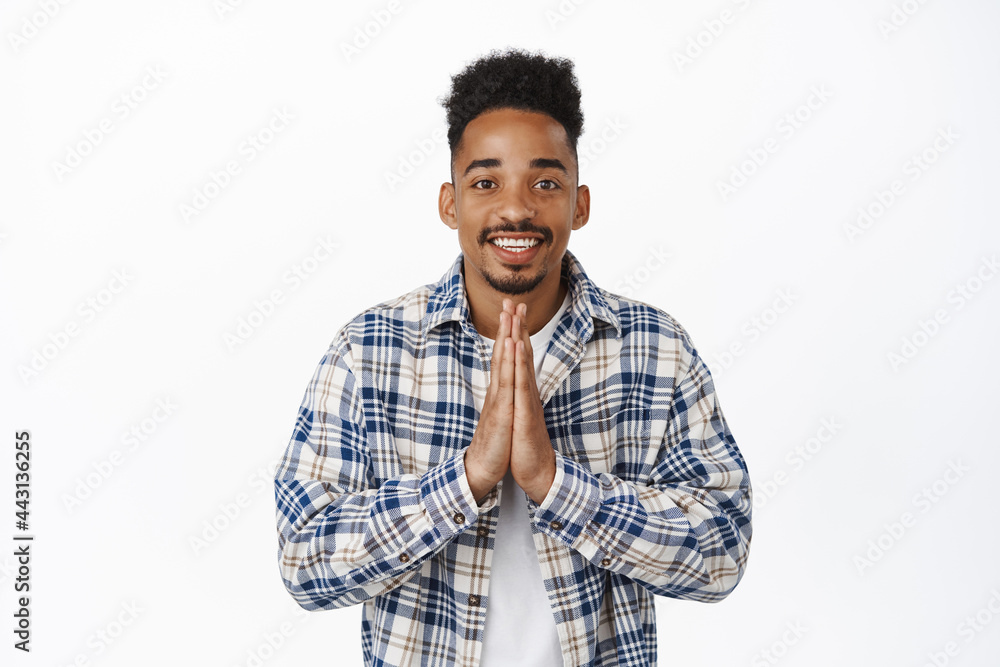 Thankful african american guy, showing namaste, beg gesture and smiling happy, appreciate opportunity, express gratitude, standing pleased against white background Thankful african american guy, showing namaste, beg gesture and smiling happy, appreciate opportunity, express gratitude, standing pleased against white background