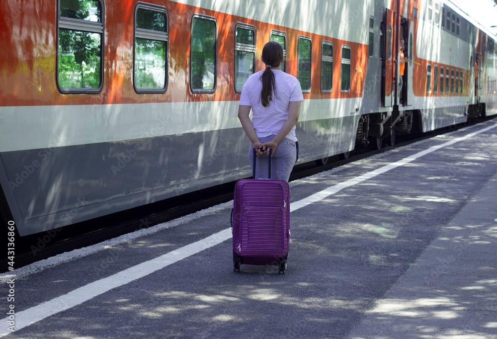 A girl with a suitcase at the train car is ready to travel