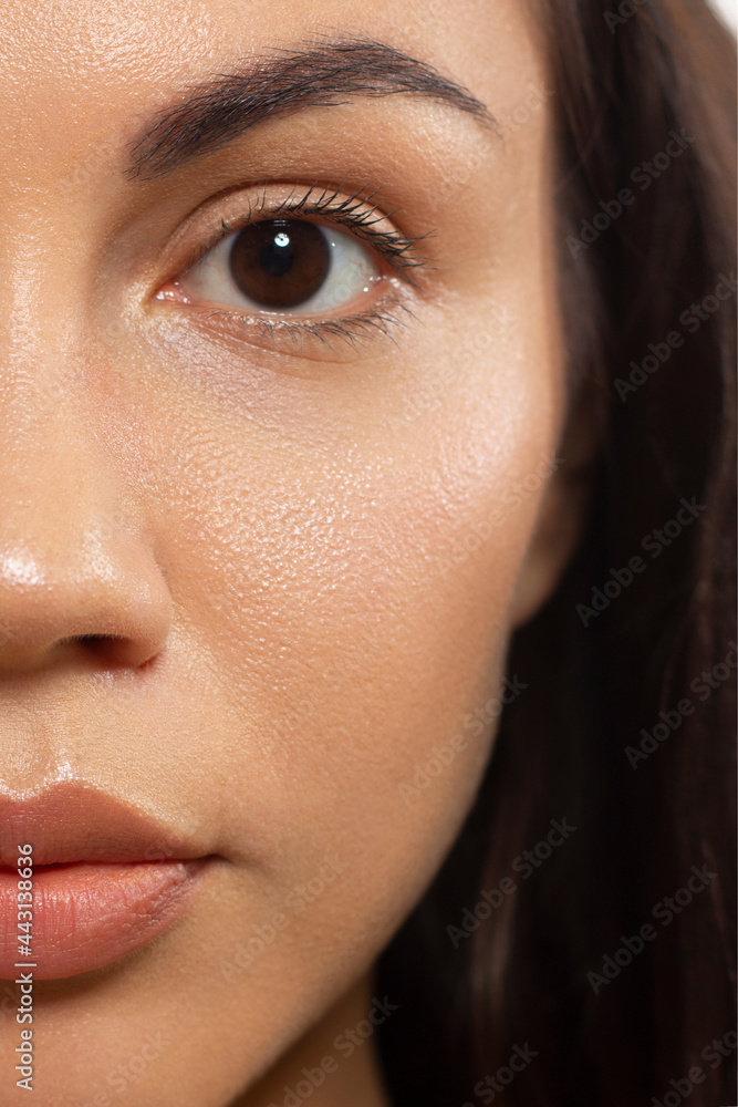 Close up beauty of a half face of a woman with wet radiant skin and big gray eyes. Fashionable natural makeup and wet facial hair. Pink lipstick with kissed lips Close up beauty of a half face of a woman with wet radiant skin and big gray eyes. Fashionable natural makeup and wet facial hair. Pink lipstick with kissed lips