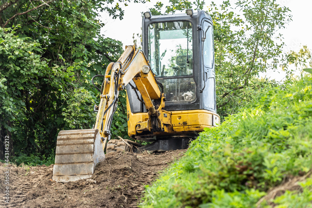 A mini excavator on a building yard in a garden A mini excavator on a building yard in a garden