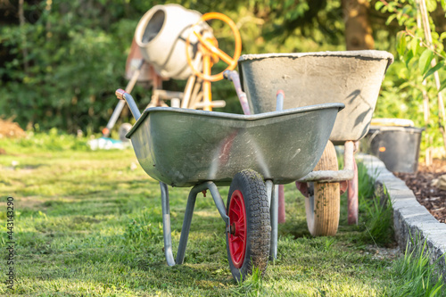A wheelbarrow in front of a building lot at a garden