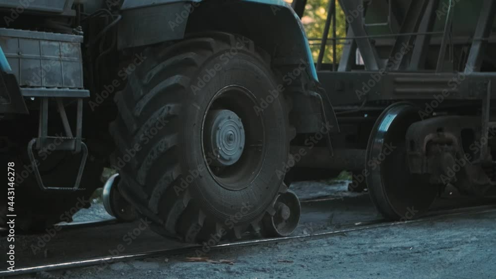 A tractor pushes railway cars along the rails A tractor pushes railway cars along the rails