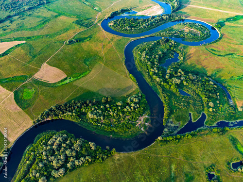 Aerial view of curve blue river with trees on the fields