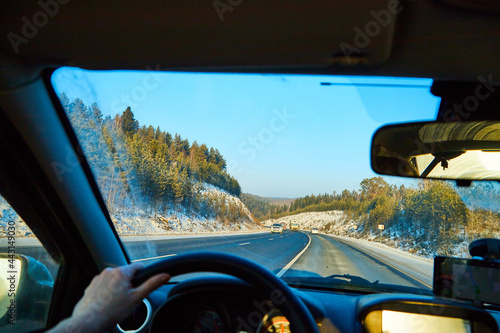 View from of car interior from side of driver to the road and nature landscape through the windshield