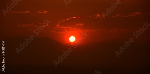 fiery red sunset over the front range of the rocky mountains through the smoky haze of the colorado wildfires, as seen from broomfield, colorado © Nina