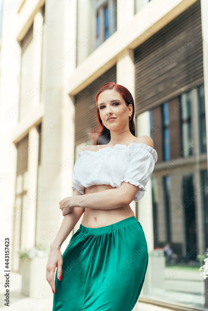 Portrait of thirty years old happy red-haired girl in summertime on the background of a modern building Portrait of thirty years old happy red-haired girl in summertime on the background of a modern building