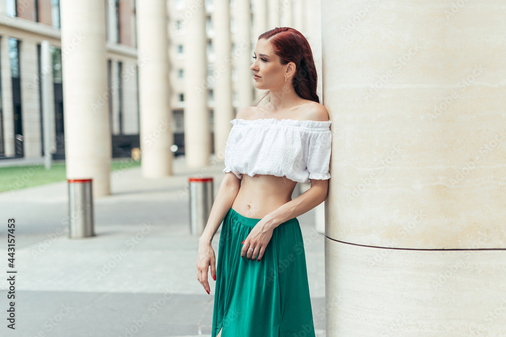 A girl of thirty with red hair next to a fancy building in the summertime A girl of thirty with red hair next to a fancy building in the summertime