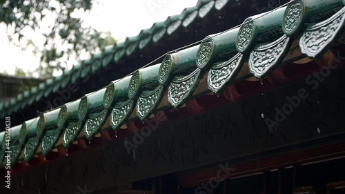 Raindrops fall from the eaves of an ancient building in slow motion