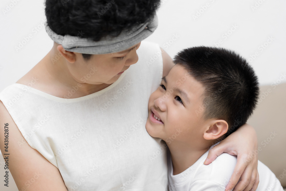 Cute Asian little boy son congratulating his mom happy with Mothers day, giving her handmade greeting postcard with red heart while sitting together on sofa at home. Family holidays concept Cute Asian little boy son congratulating his mom happy with Mothers day, giving her handmade greeting postcard with red heart while sitting together on sofa at home. Family holidays concept
