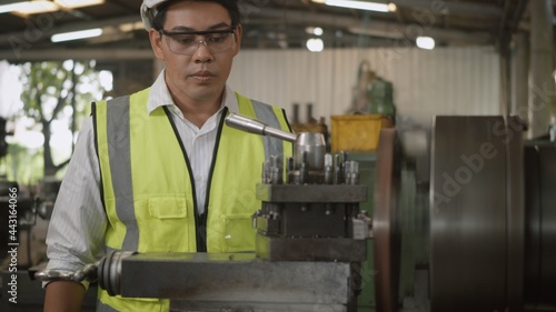 Asian professional mechanical engineer or operation man wear uniform goggles safety working on workshop metal lathe industrial manufacturing factory, Heavy industry lathe worker man,