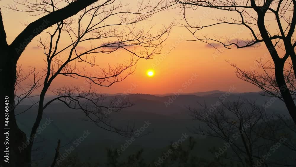 Time-lapse of sunset, withered tree branches in winter in foreground Time-lapse of sunset, withered tree branches in winter in foreground