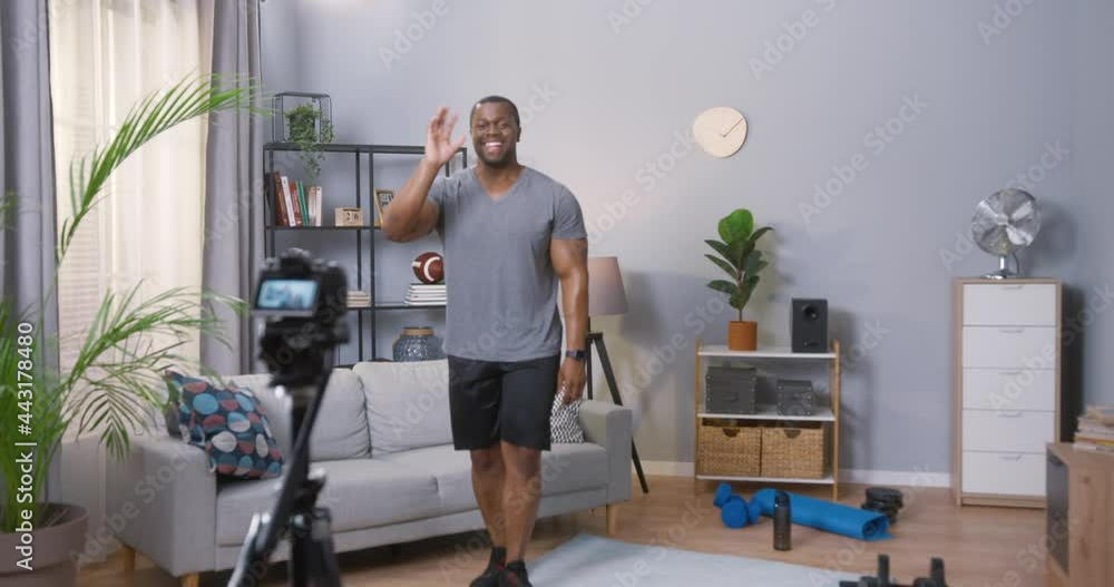 Young man blogger showing at his abdominal muscles while recording his daily video blog. Blogger using a camera mounted on a tripod to record her video about sport Young man blogger showing at his abdominal muscles while recording his daily video blog. Blogger using a camera mounted on a tripod to record her video about sport