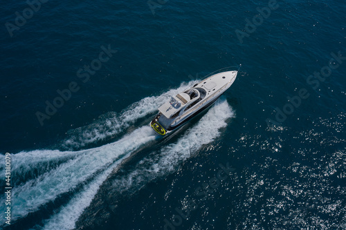 Luxury motor boat on dark blue water aerial view. The yacht is fast moving on dark water. Large white yacht on the water in motion top view. © Berg