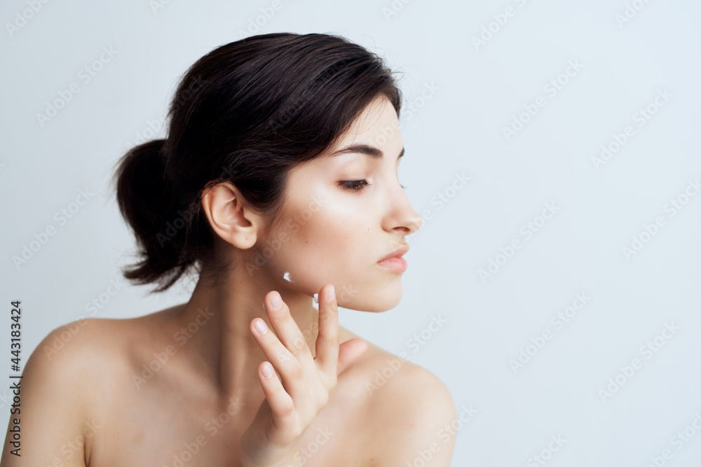woman with bare shoulders holds hand near face clean skin close-up woman with bare shoulders holds hand near face clean skin close-up