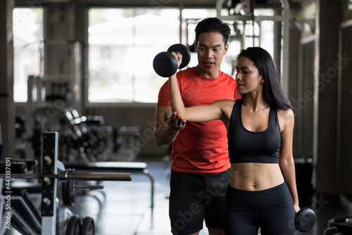 trainer set biceps dumbbell position to girl in gym