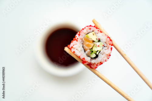 sushi sticks keep roll with a cup of soy sauce on white background