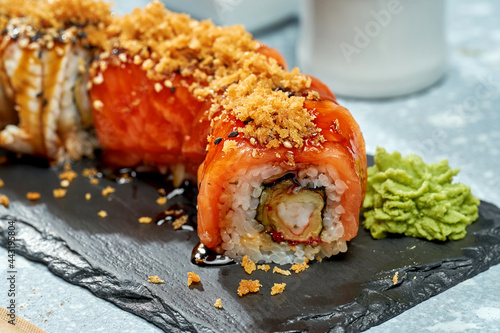 Sushi roll philadelphia with salmon, shrimp and eel on a black plate on a light background