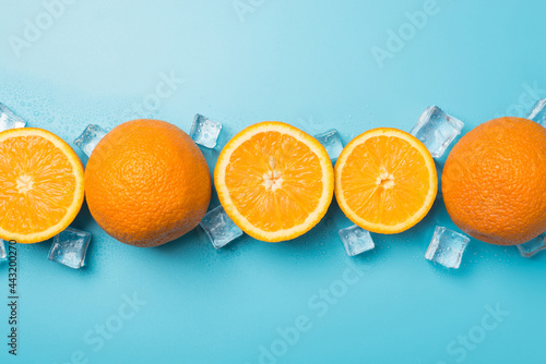 Top view photo of cut and whole oranges and ice cubes in raw on isolated pastel blue background with copyspace