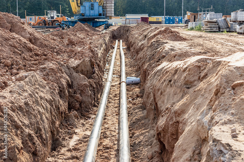 Laying heating pipes in a trench at construction site. Energy efficient insulated pipes. Cold and hot water, heating and heating system of apartments in the house. photo