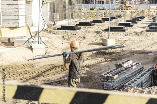 A worker transfers elements for the installation of the formwork at the construction site. Monolithic concrete formwork during the construction of a residential building.