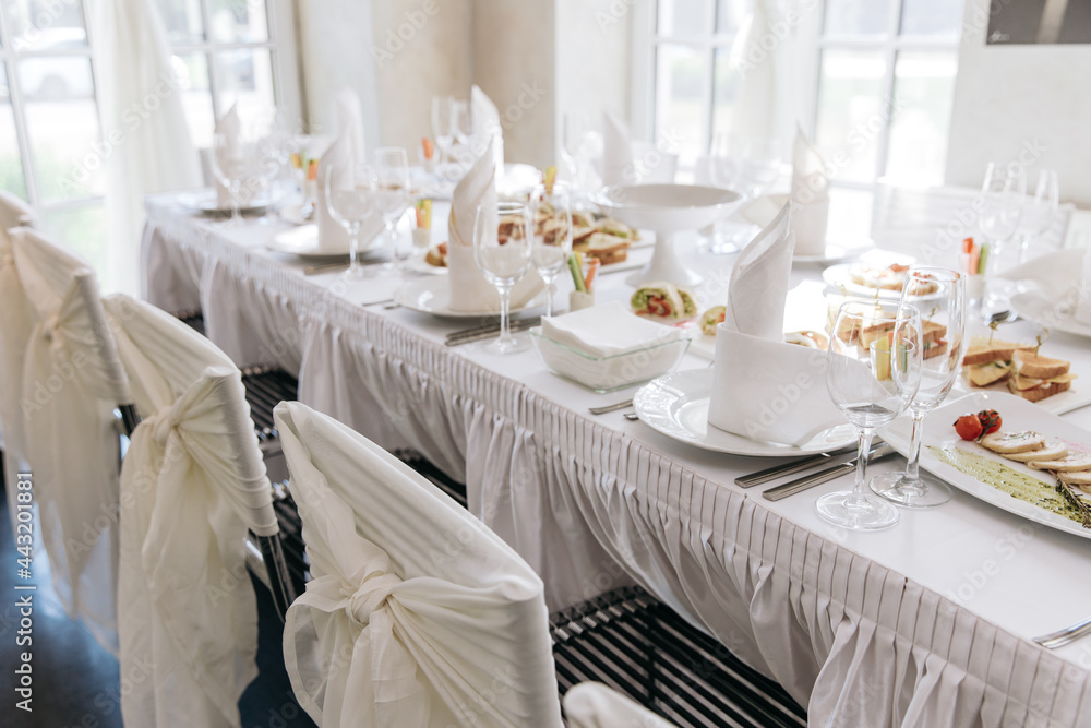 Table setting for a banquet or celebration. Empty wine glasses for spirits, champagne and juice. Set the table. Cloth napkins on a platter. Banqueting hall. Cold appetizers and salads