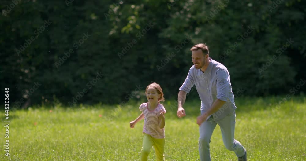 Father chasing his cute little daughter while playing in the park Father chasing his cute little daughter while playing in the park