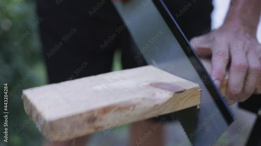 Carpenter cutting wood plank using hand saw, cutting off wood block making wooden clock, 2x slow motion, close-up Carpenter cutting wood plank using hand saw, cutting off wood block making wooden clock, 2x slow motion, close-up