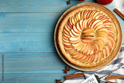 Flat lay composition with delicious homemade apple tart on light blue wooden table. Space for text