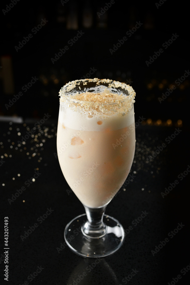 bartender special cold peanut or almond cocktail mocktail with fresh coconut milkshake juice in tall glass goblet on black background luxury hotel pub iced beverage menu bartender special cold peanut or almond cocktail mocktail with fresh coconut milkshake juice in tall glass goblet on black background luxury hotel pub iced beverage menu