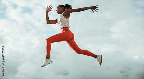 Athletic woman running and jumping outdoors © Jacob Lund