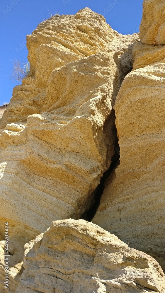 vertical crack in the rock, sandstone rock against blue sky