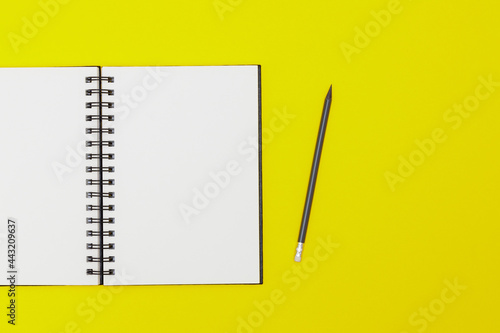 Blank spiral notebook and pencil on yellow background. Top view with copy space for input the text.