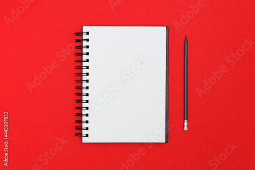 Blank spiral notebook and pencil on red background. Top view with copy space for input the text. photo