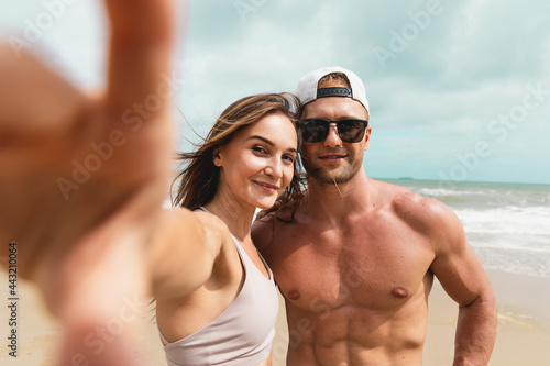 Happy young sport couple taking a selfie by smartphone at the seaside