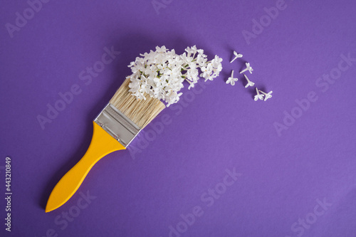 wooden yellow paint brushes and white flowers of lilac on a dark purple background