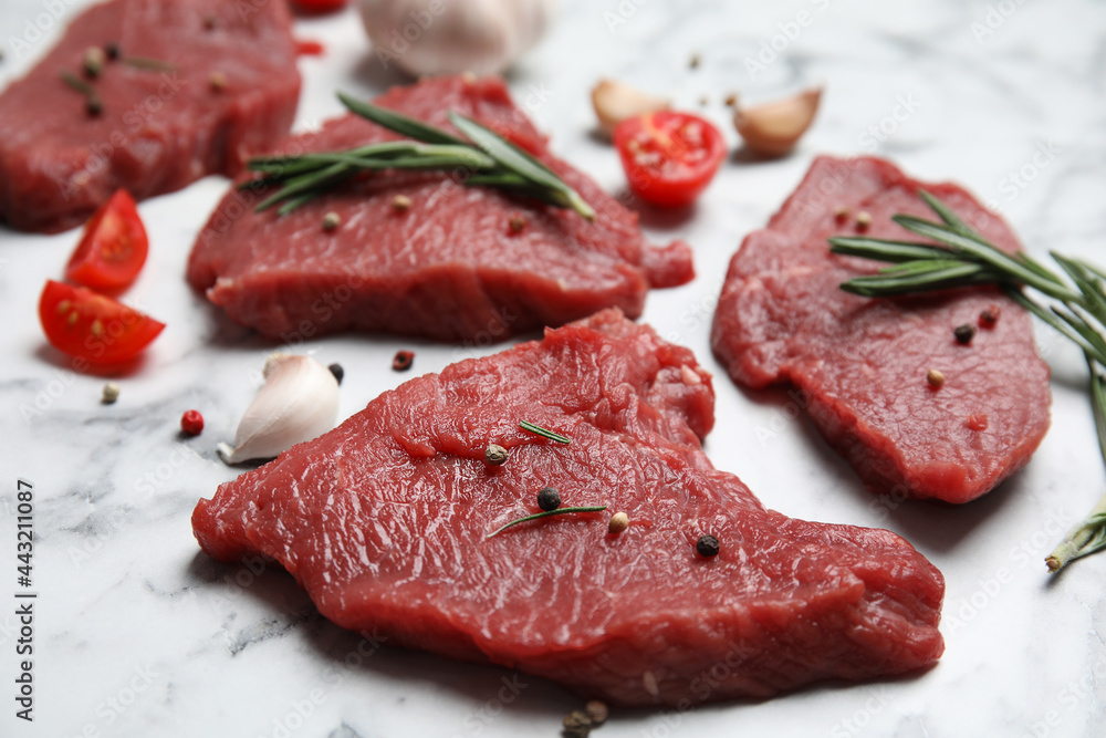 Fresh raw meat steaks and spices on white marble table, closeup Fresh raw meat steaks and spices on white marble table, closeup