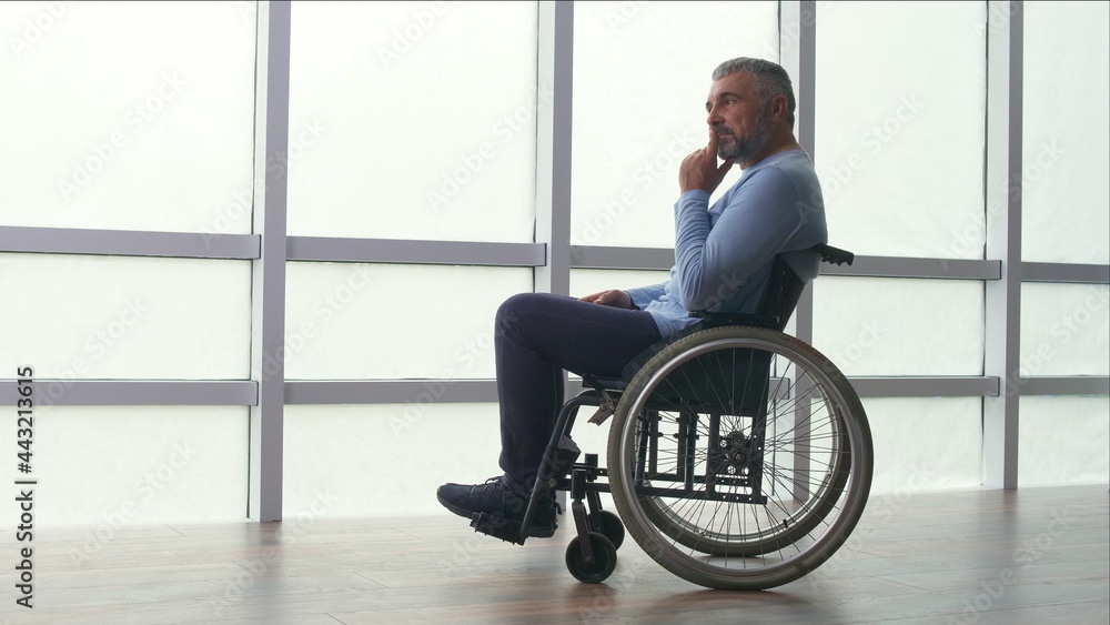 Depressed Middle-aged Lonely Man, Frustrated Mature Man, Sitting Alone in a Wheelchair By the Window. Solitude, Care, Retirement, Injury, Disability. Rehab Client, Hard Recovery. Depressed Middle-aged Lonely Man, Frustrated Mature Man, Sitting Alone in a Wheelchair By the Window. Solitude, Care, Retirement, Injury, Disability. Rehab Client, Hard Recovery.