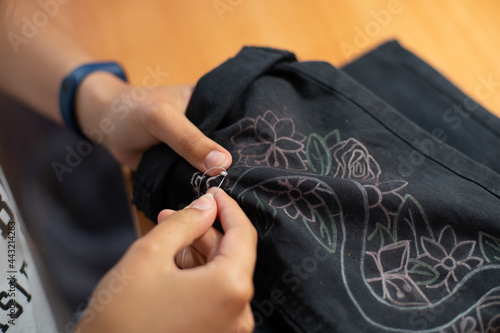 Young girl s hands embroidering black pants  craft