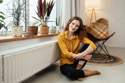 Cute young woman relaxing on the floor near a warm radiator photo